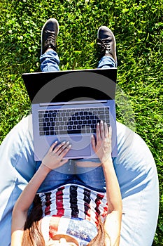 Top view. Woman working on laptop pc computer with blank black empty screen to copy space in park on green grass