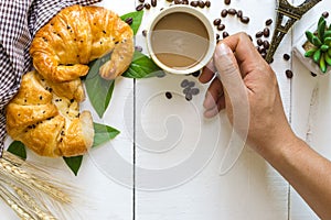 Top view hands of man eating coffee and croissant with coffee be