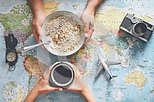 Top view hands people planning vacation with world map while doing breakfast with cereal milk