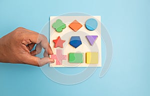 Top view Hands Picking up one Colorful Wooden building blocks in different shapes on blue background.
