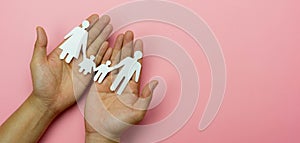 Top view of Hands protect chain family paper on pink background. Family care insurance concept, love and charity, security life,