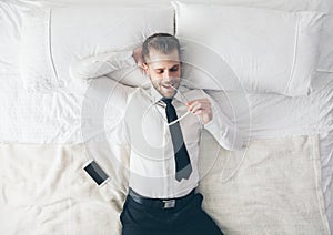 Top view. Handsome businessman with glasses lying on bed