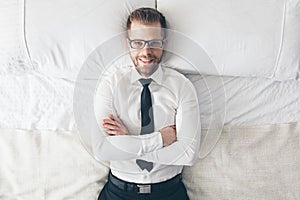 Top view. Handsome businessman with glasses lying on bed