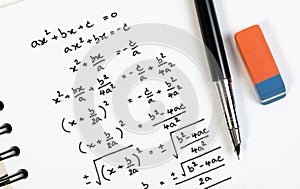 Top view of handwriting of mathematics quadratic equation formula on examination, practice, quiz or test in math class.