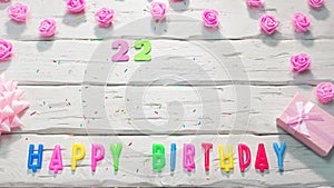 Top view of happy birthday 22 candle letters for a girl in pink shades with beautiful rose flowers, postcard congratulation copy