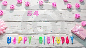 Top view of happy birthday 54 candle letters for a girl in pink shades with beautiful rose flowers, postcard congratulation copy