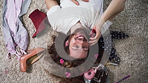 Top view of happy caucasian intersex person lying on soft carpet and talking on the phone. Portrait of binary gender man