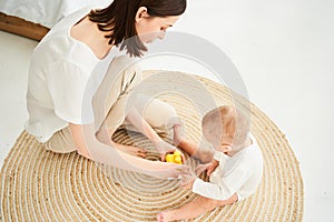 Top view, happy caucasian mother and her little son play together on the floor at home