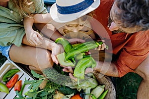 Top view of happy family holding their harvest, fresh vegetable. Sitting in their garden.