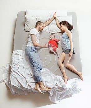 Top view of happy family with one newborn child in bedroom.