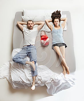 Top view of happy family with one newborn child in bedroom.