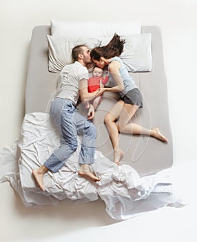 Top view of happy family with one newborn child in bedroom.