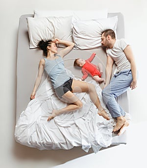 Top view of happy family with one newborn child in bedroom.