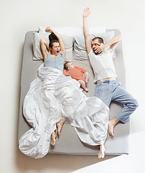 Top view of happy family with one newborn child in bedroom.