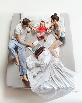 Top view of happy family with one newborn child in bedroom.