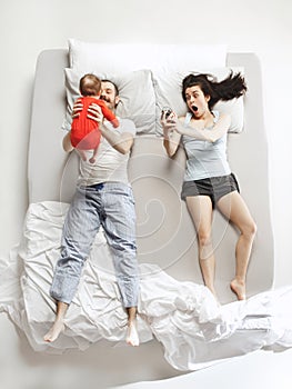 Top view of happy family with one newborn child in bedroom.