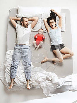 Top view of happy family with one newborn child in bedroom.