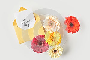 top view of happy mothers day greeting card and beautiful gerbera flowers