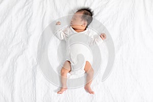 Top view happy newborn baby lying sleeps on a white blanket comfortable and safety at warmth place. Cute Asian newborn sleeping