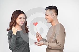 Top view of happy young couple looking at each other and smiling . Girl is holding a red paper heart