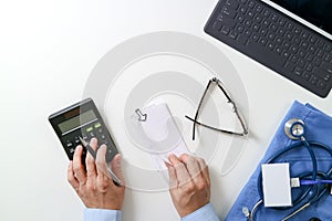 top view of Healthcare costs and fees concept.Hand of smart doctor used a calculator for medical costs in modern hospital