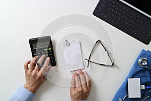 top view of Healthcare costs and fees concept.Hand of smart doctor used a calculator for medical costs in modern hospital