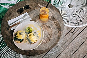 Top view of Healthy Breakfast with Bread Toast and Poached Egg with spinach, avocado on wooden table. Orange smoothie