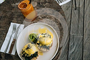 Top view of Healthy Breakfast with Bread Toast and Poached Egg with spinach, avocado on wooden table and orange smoothie