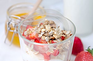 Top view healthy breakfast of homemade granola cereal with milk, strawberry, nuts and fruit, honey with drizzlier on