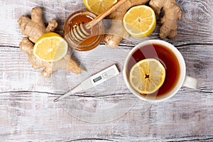 Top view. Healthy concept. Tea, lemon, ginger,thermometer, honey on a white wooden background. Flat lay. Treatment of