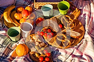 Top view of healthy picnic food on wooden board on blanket outdoors at sunny summer day