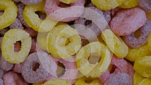 Top view: heap of colorful cereal loop rings on rotating surface - close up