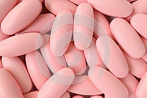 Top view of heap of light pink color oval shaped pills for background or banner