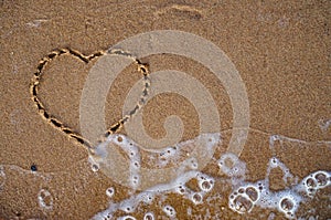 Top view of heart drawn on sand beach with the wave of sea. Beach background