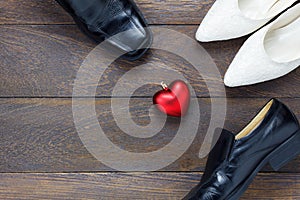 Top view heart shape with men`s shoes and women`s shoes on wood