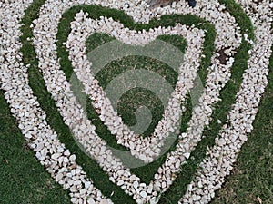 Top view of heart shape white stones on the grass for landscape design. Backdrop for Valentineâ€™s day or romantic background