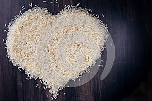 Top view heart symbol of parboiled rice on black background