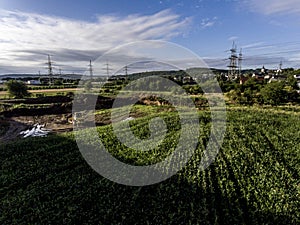 Top view heavy machine excavator bagger working in mud on construction site with green landscape surrounding