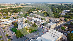 Top view historic Hood County Courthouse and Clock Tower and lush green neighborhood in Granbury, Texas, USA