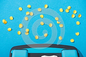 Top view of holepunch with paper circles on blue background.