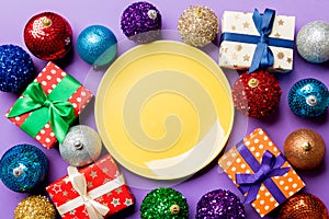 Top view of holiday setting on colorful background. Plate, gifts, baubles and Christmas decorations. New Year dinner concept