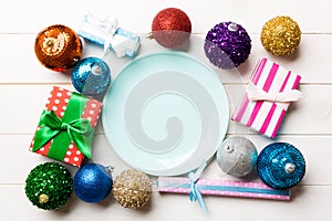 Top view of holiday setting on wooden background. Plate, gifts, baubles and Christmas decorations. New Year dinner concept