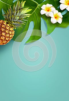 Top view of holiday travel beach with pineapple, flower plumeria and monstera leaves on blue background