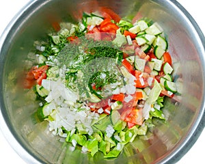 Top view of home grown salad ingredients in metal bowl. Unseasoned cucumber, tomato, onion and dill