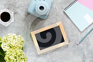 Top view home office desk with feminine accessories and devices. Flat lay blank picture frame, paper notepad, instant film camera