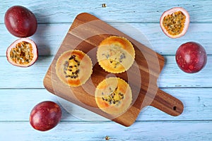 Top View of Homemade Passion Fruit Muffins on Breadboard with Fresh Ripe Passion Fruits Scattered on Wooden Table