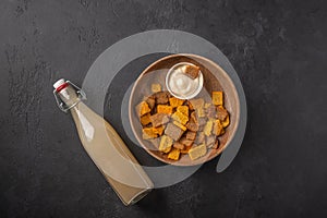 Top view homemade tradishional russian light rye kvass in bottle and crackers on dark wooden background. Wonderful