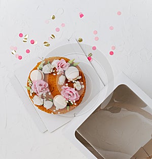 Top view of a honey cake with flowers on a box base next to windowed top