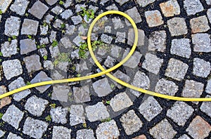 Top view of hosepipe on grass and cobblestone surfaces. Minimalistic conception