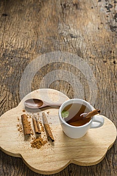 Top view hot apple juice in cup with cinnamon and ground cinnamon on old wood.